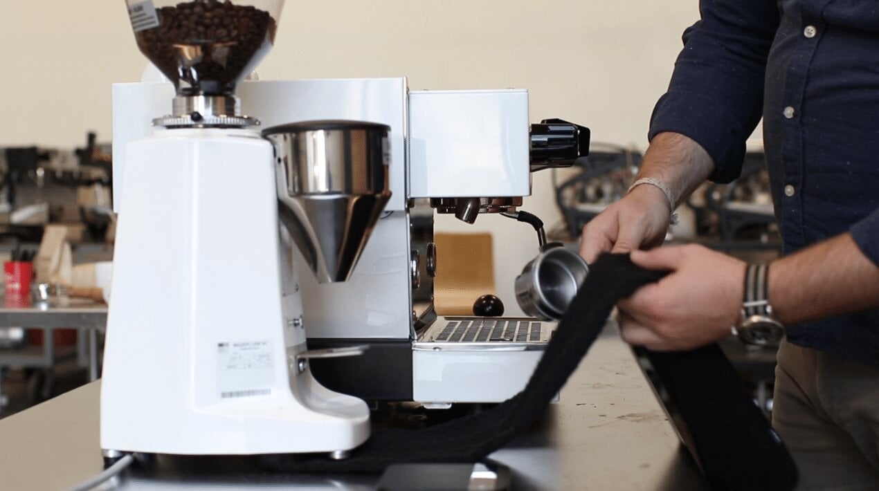 La Marzocco espresso machine with steam wand and portafilter in use, barista preparing espresso