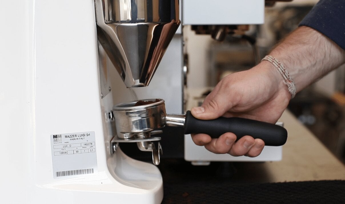 Barista using a La Marzocco espresso machine portafilter with group head, detail shot