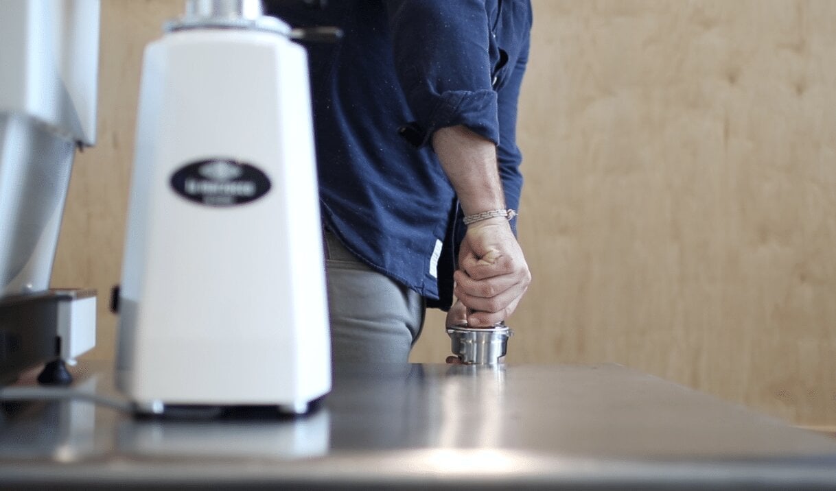 Pouring espresso into a cup with La Marzocco espresso machine in background