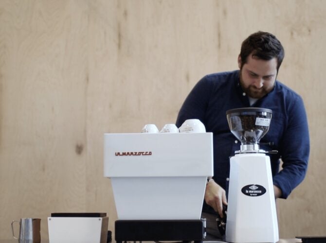 Man using La Marzocco espresso machine and grinder in a home barista setup