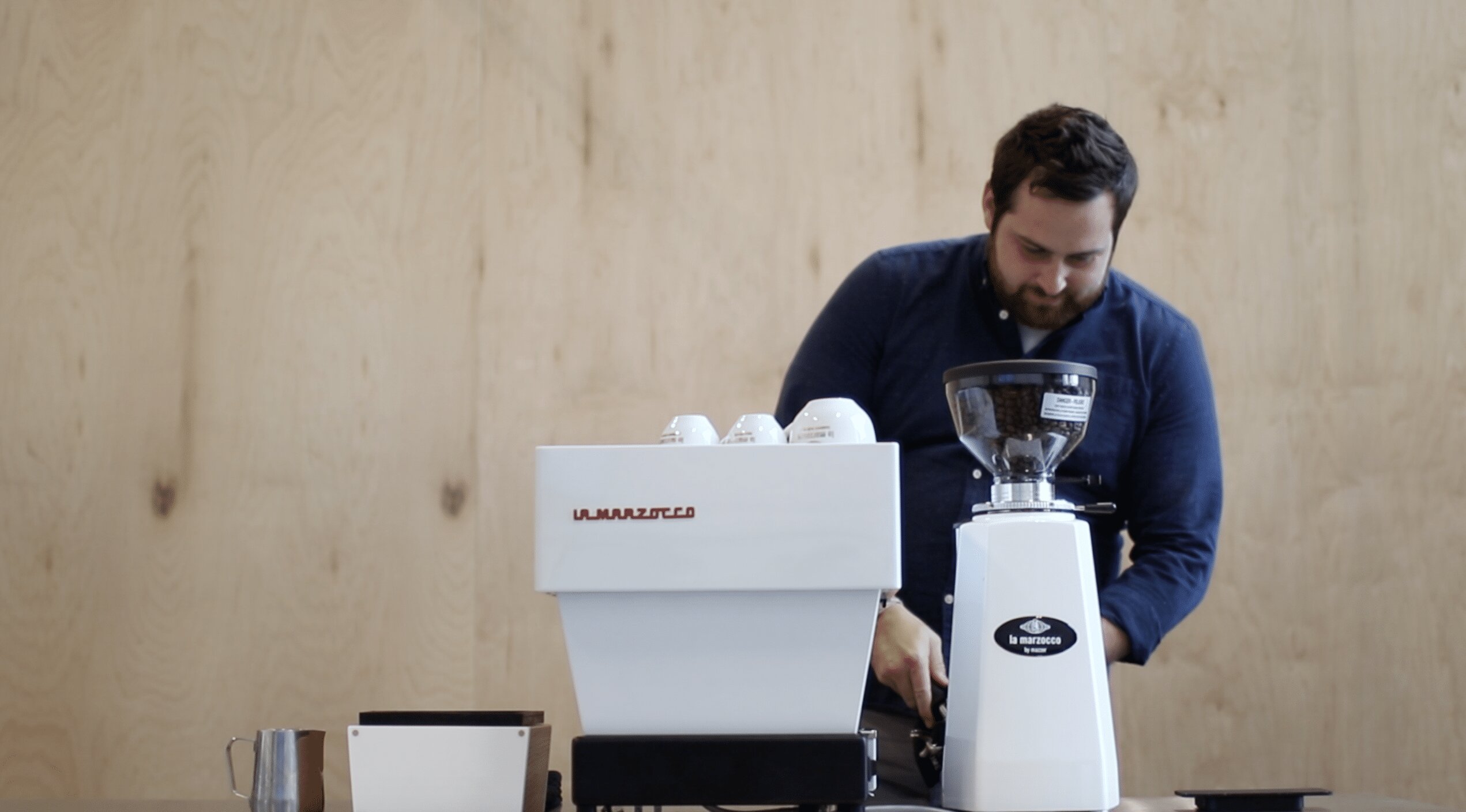 Man using La Marzocco espresso machine and grinder in a home barista setup