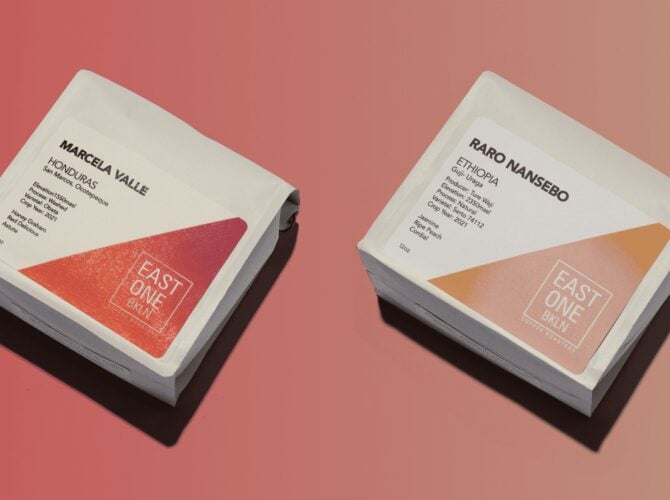 Two specialty coffee bags on coral background: Marcela Villegas Ethiopia single-origin on left with red accent, Raro Nansebo Ethiopia on right with tan accent, both branded with East One Coffee logo