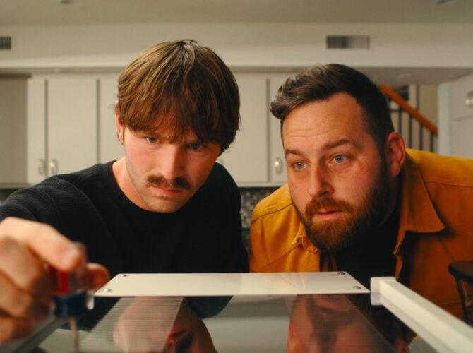 Two men examining a La Marzocco Linea Mini espresso machine in a home kitchen setting
