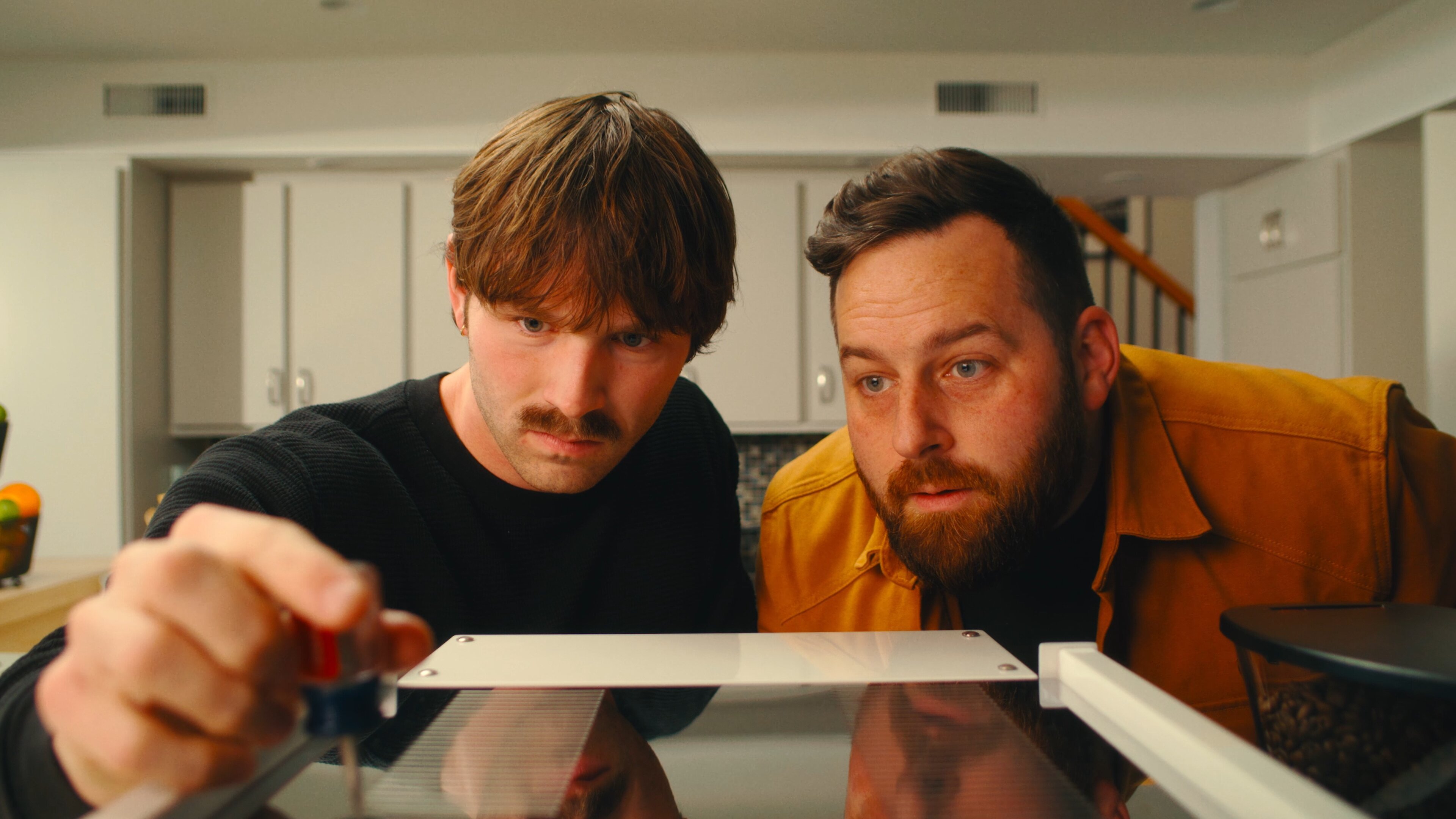 Two men examining a La Marzocco Linea Mini espresso machine in a home kitchen setting