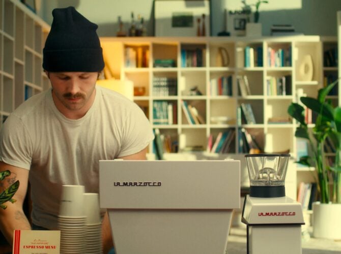 Man setting up a La Marzocco Linea Mini espresso machine at a pop-up bar in a modern home kitchen with bookshelves