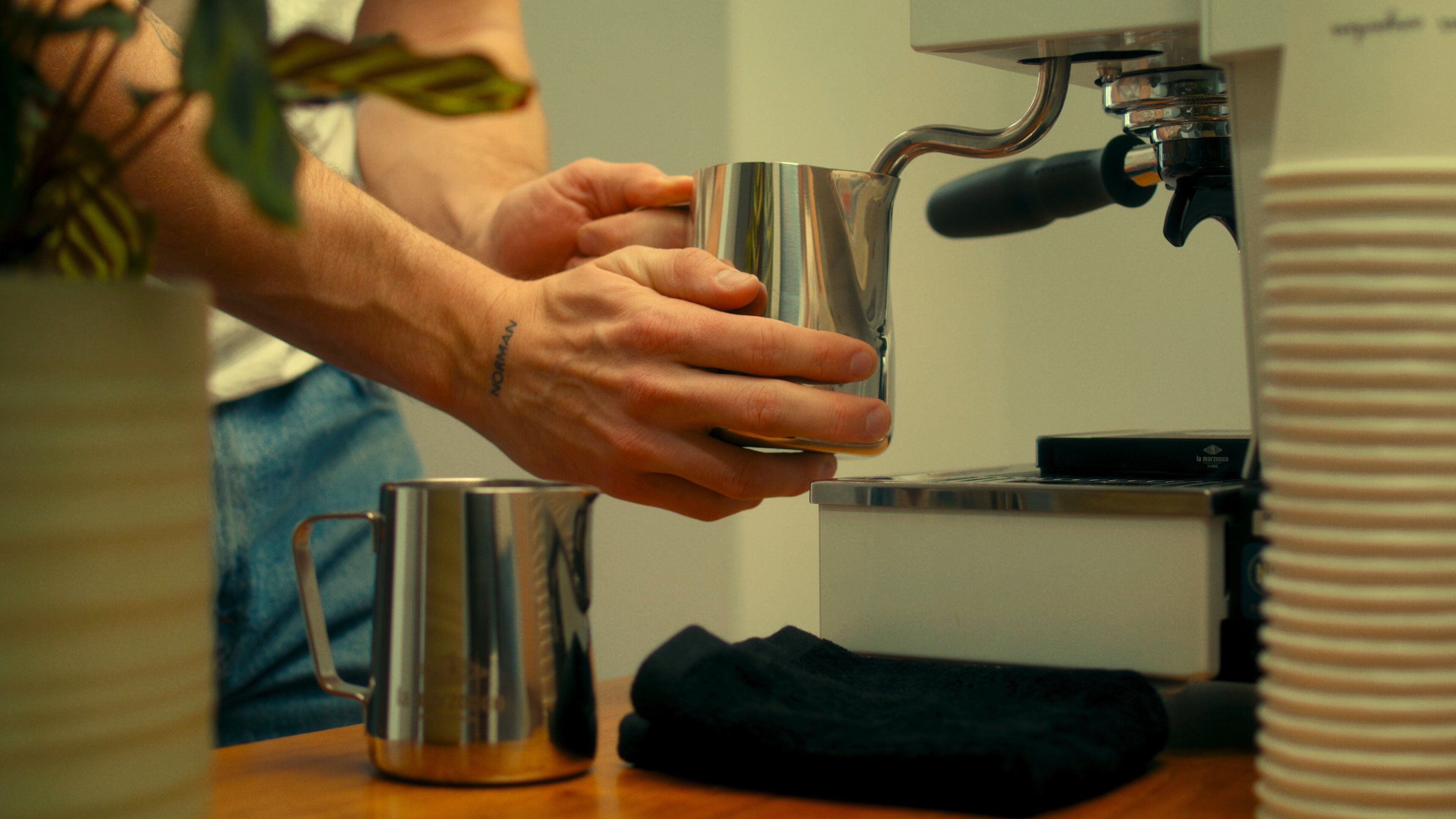 Person pouring espresso into a stainless steel pitcher from a La Marzocco Linea Mini espresso machine with double steam wand