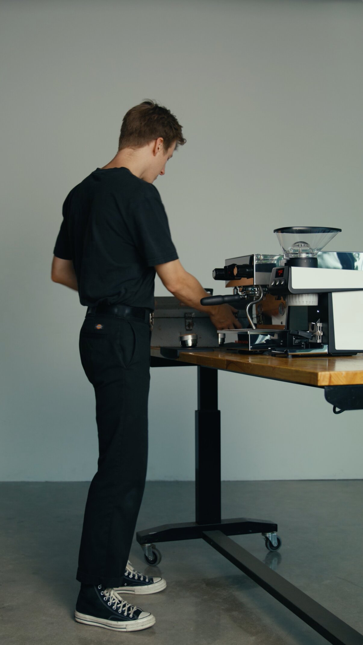 Barista operating a La Marzocco espresso machine at a wooden counter