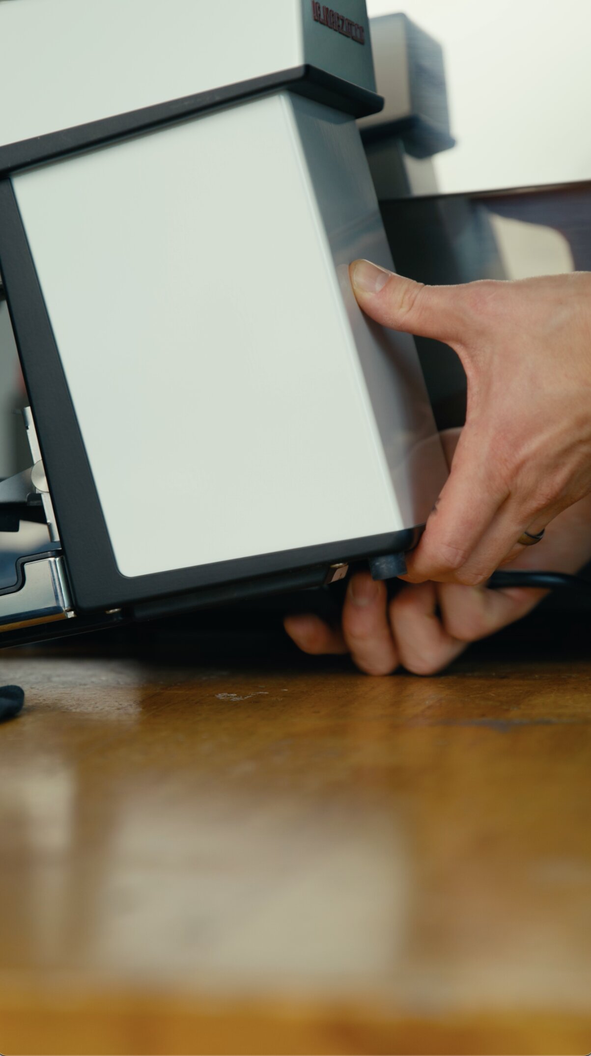 Hand holding La Marzocco Linea Micra espresso machine, angled view showing black frame and white panel