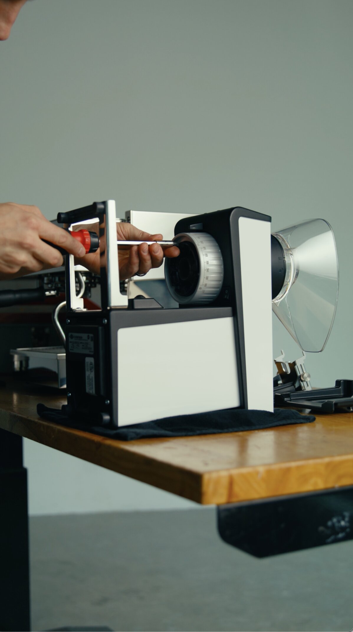 Hands operating a manual espresso grinder with portafilter, demonstrating grinding technique