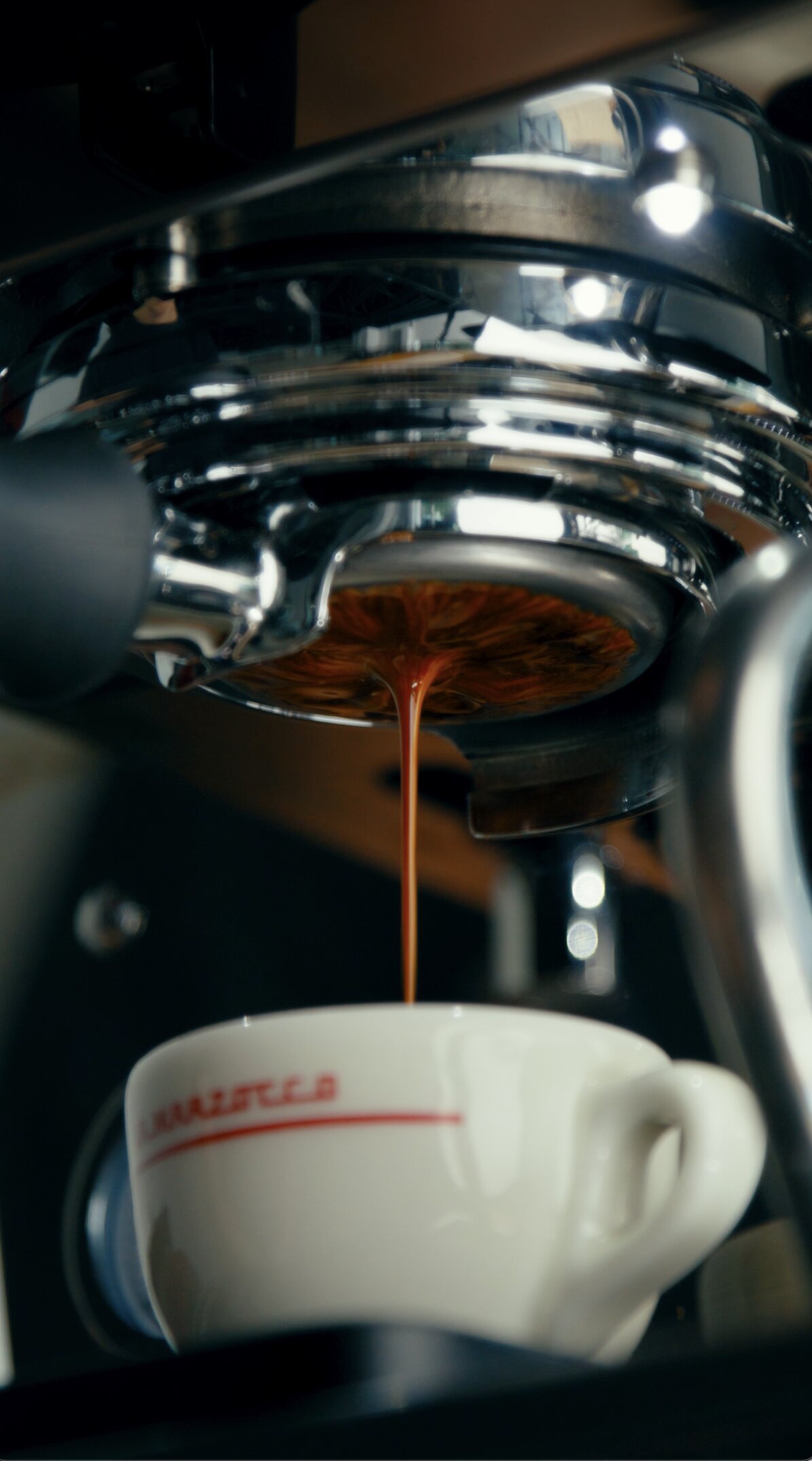 Espresso pouring from La Marzocco espresso machine group head into white cup