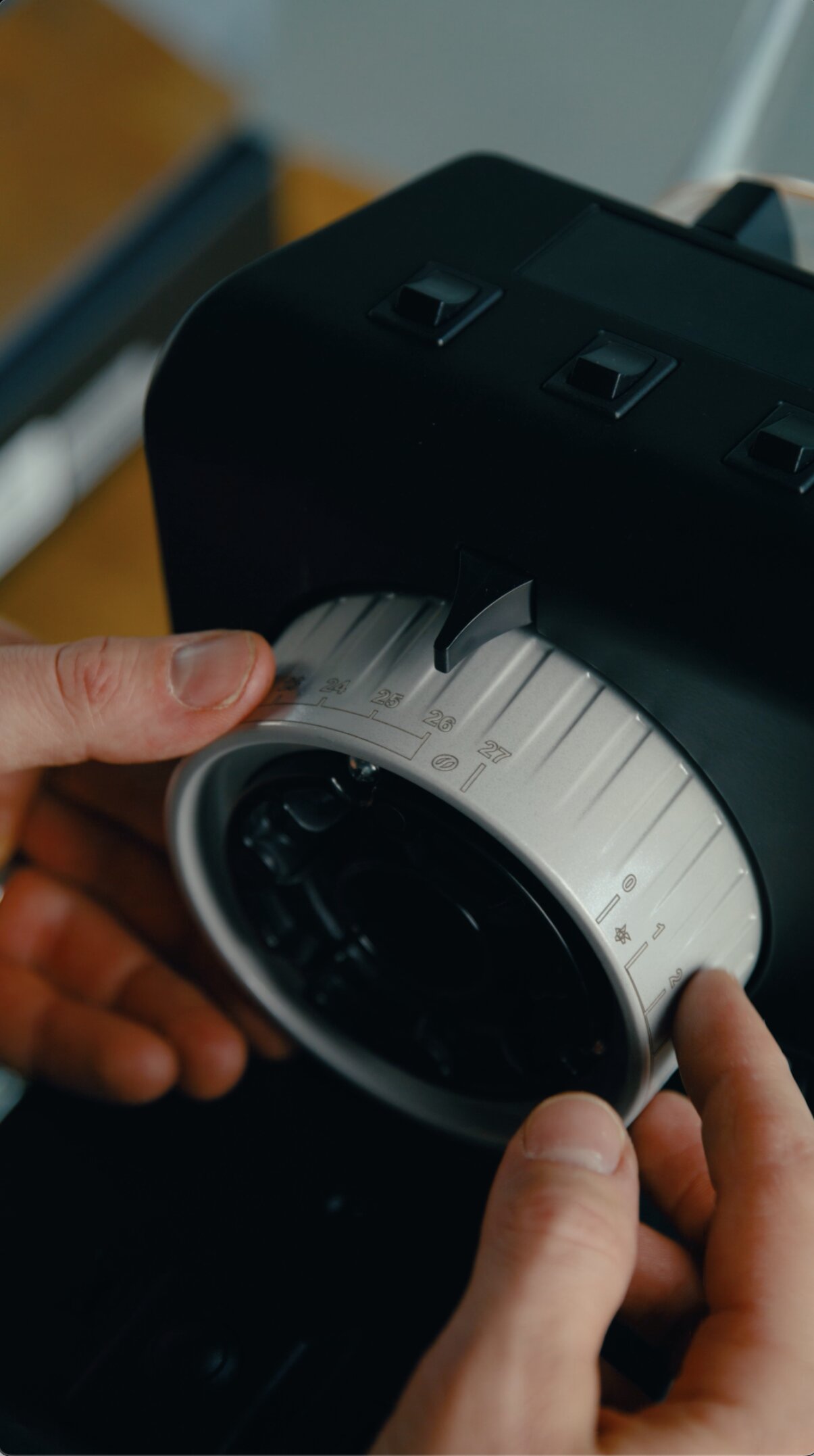 Hand adjusting the grind setting dial on a La Marzocco Pico grinder in black