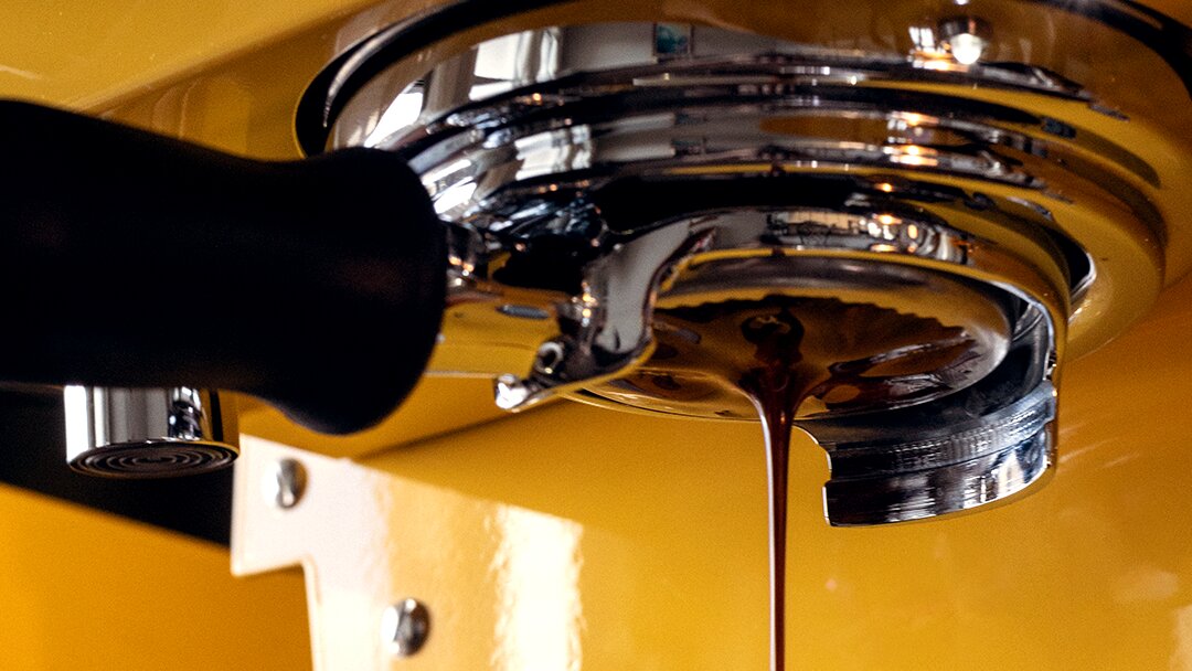La Marzocco Linea Mini espresso machine in yellow, pouring espresso into group head basket