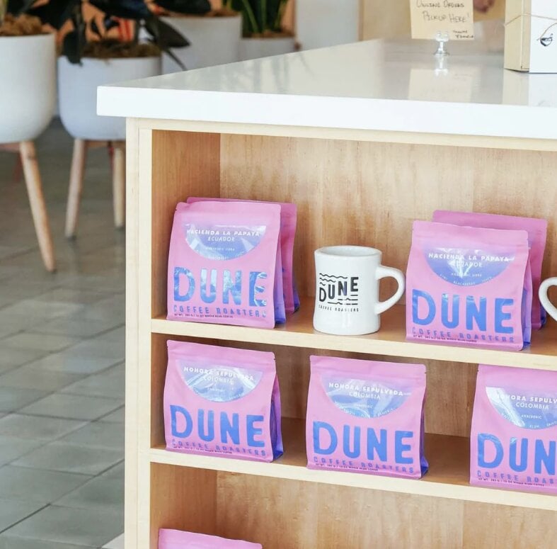 Dune coffee bags and ceramic mug displayed on wooden shelf