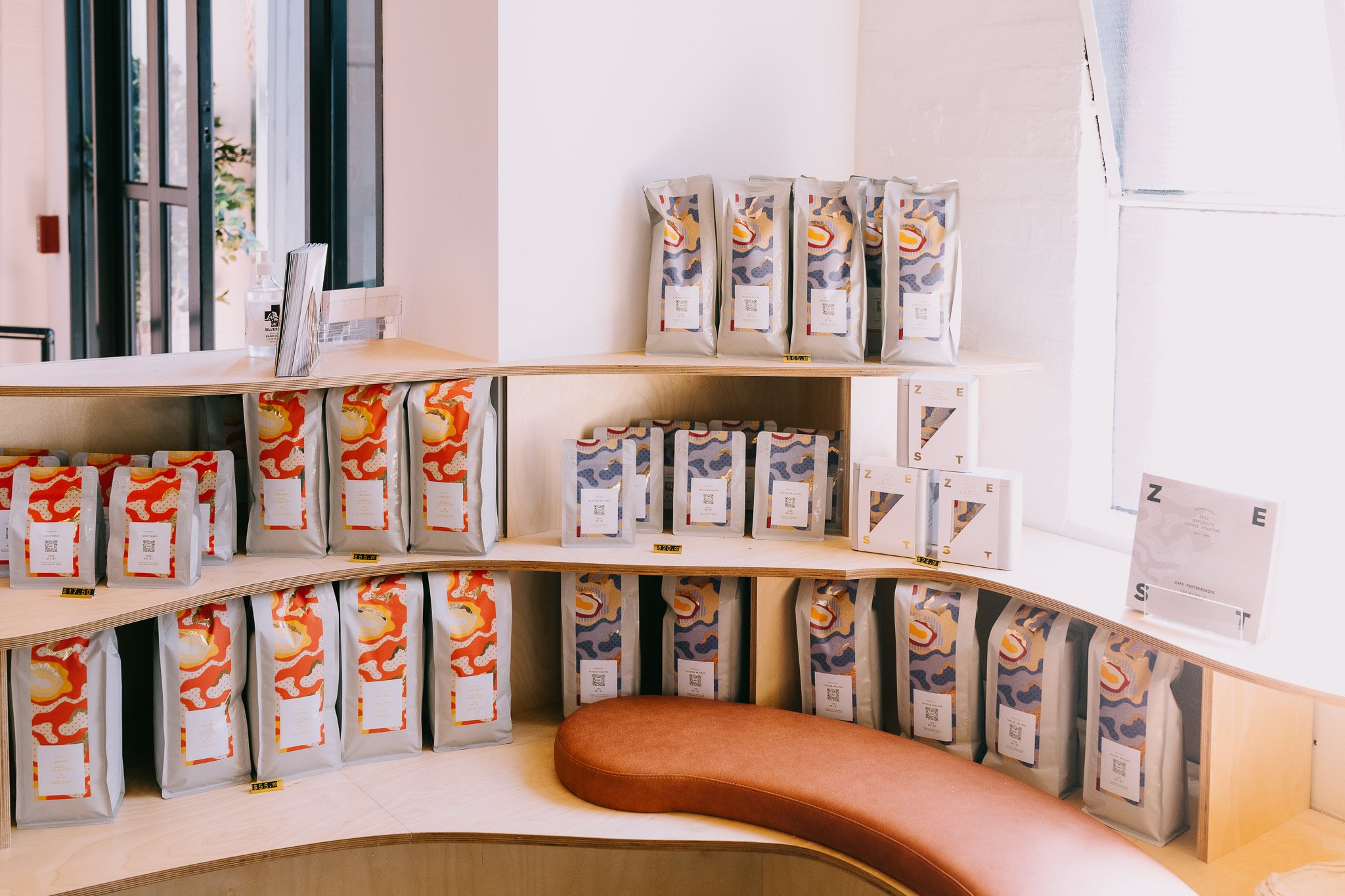 La Marzocco coffee display with packaged products on wooden curved shelving in retail showroom