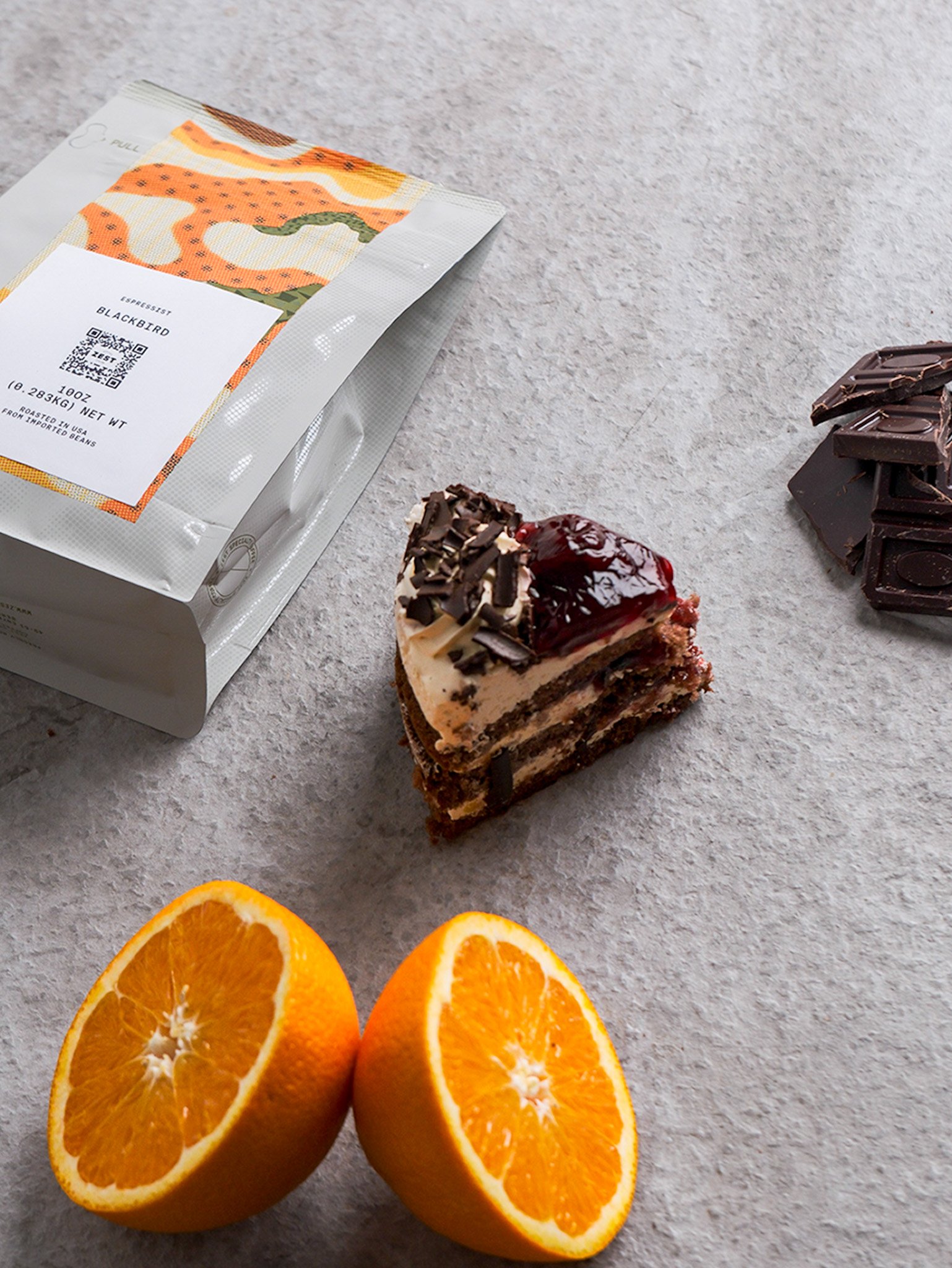 Chocolate cake with fresh orange slices and dark chocolate shards on marble surface