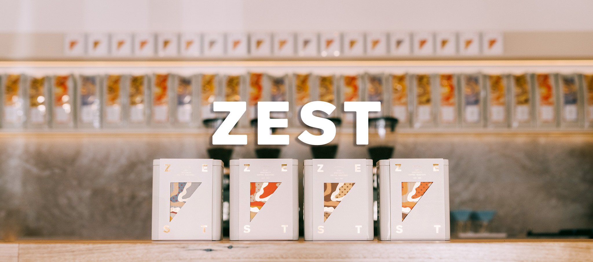 ZEST product collection display with four white boxes featuring orange and tan gradient design elements on wooden shelf
